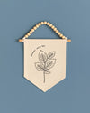 A beige banner with a black leaf design hangs against a blue background.