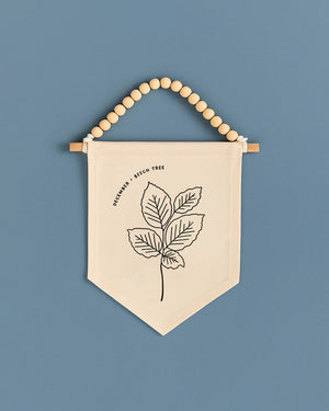 A beige banner with a black leaf design hangs against a blue background.