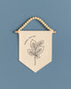 A beige banner with a black leaf design hangs against a blue background.