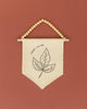 A beaded banner with a simple black and white leaf design hangs against a red background.