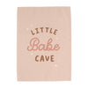 Pink towel with 'Little Bake Cave' text on a white background